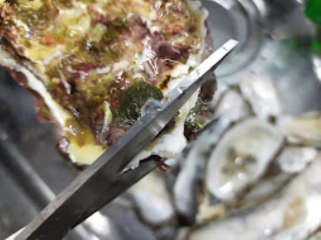 キッチンバサミで牡蠣の殻の上部を切る様子